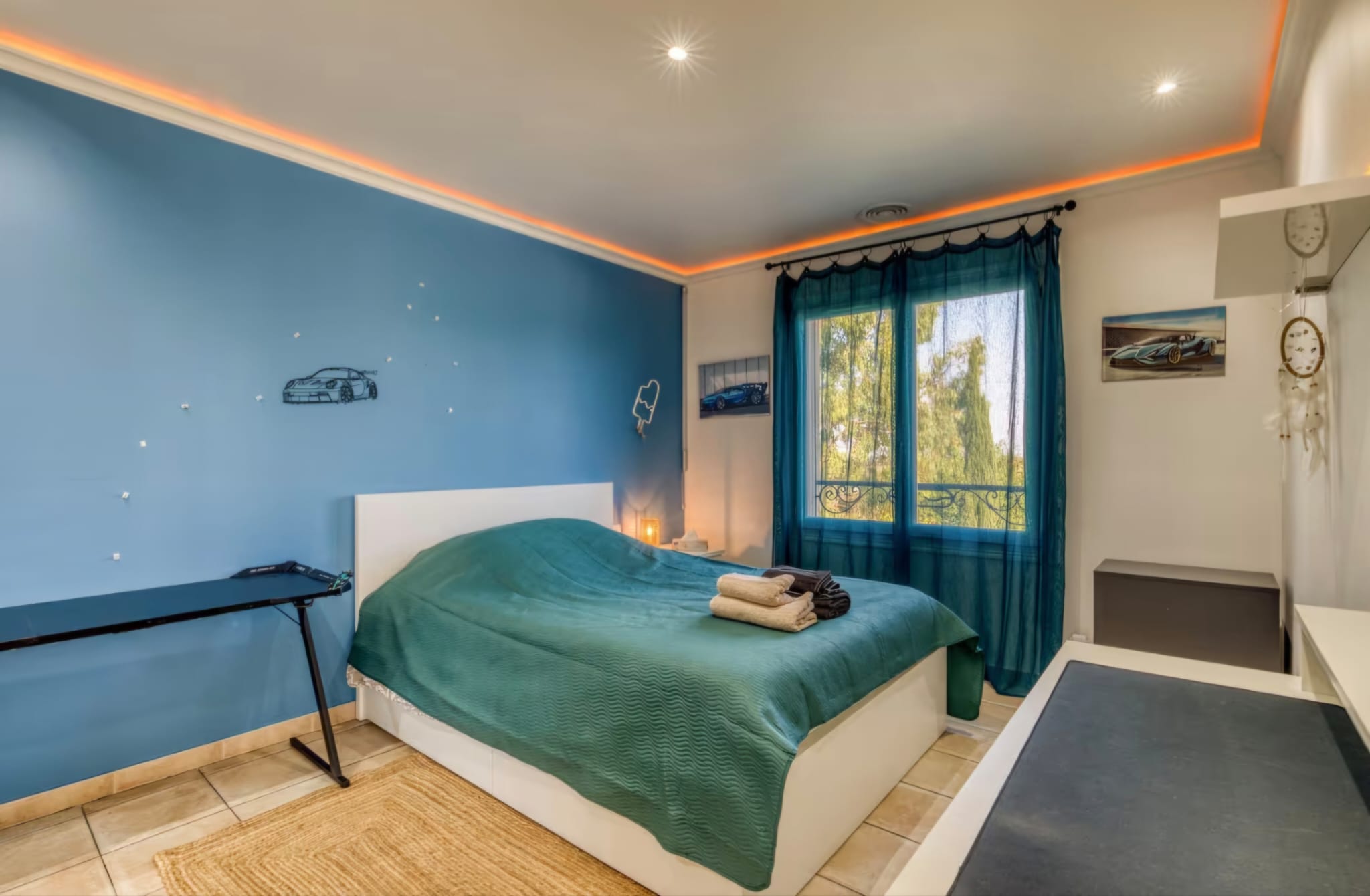 Chambre bleue avec dessins de voitures de sport sur le mur